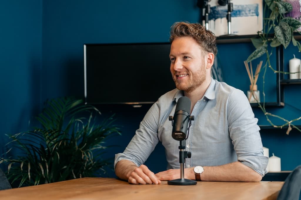 Rudy Nicola achter de microfoon in een podcaststudio